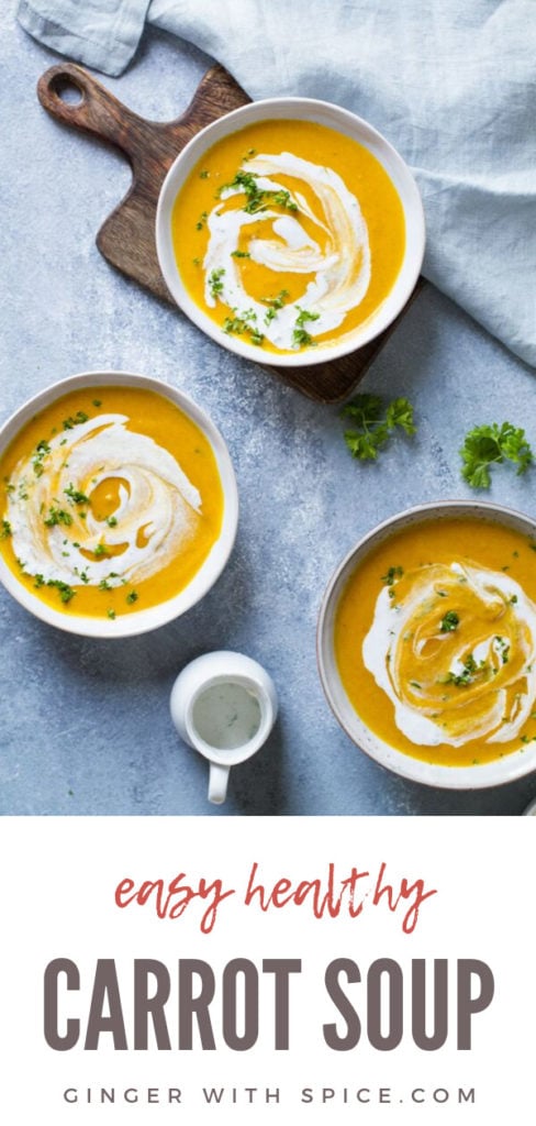 Three bowls with curry coconut carrot soup with ginger cream and parsley. Blue background. Pinterest pin.