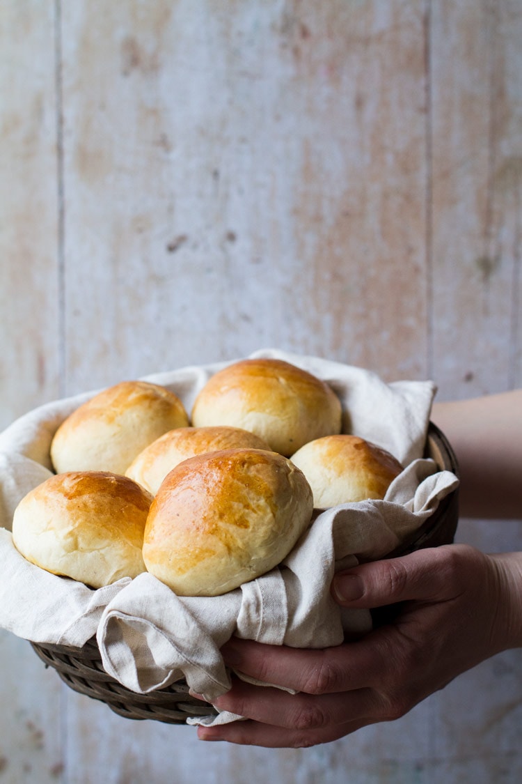 Hands holding a basket of sweet rolls.