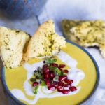 Yellow soup with pomegranate arils and ginger gream, torn naan on the side.
