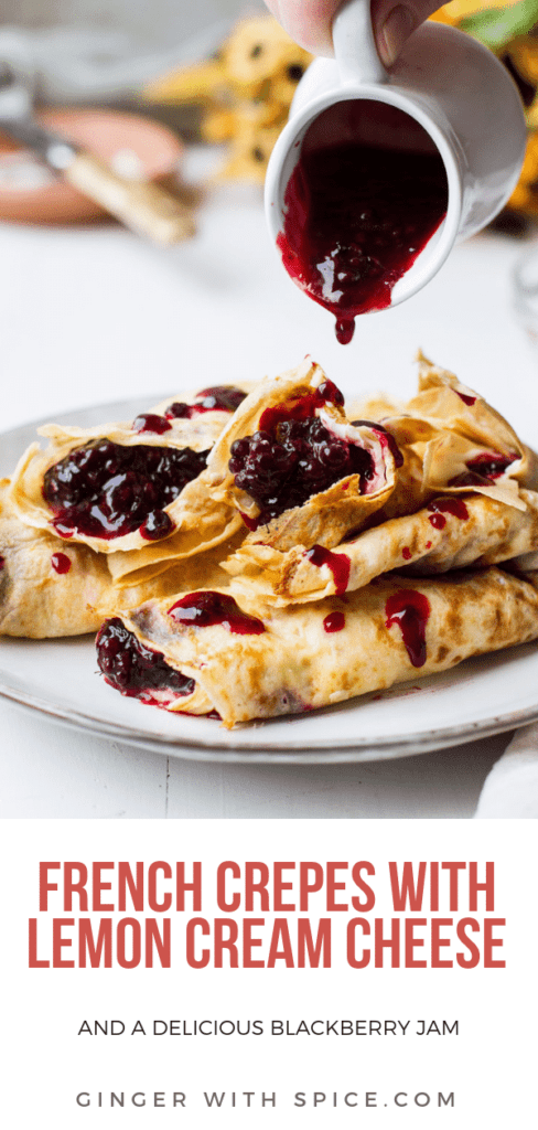 A stack of crepes filled with lemon cream cheese and blackberry jam. White plate, white background and white mug with blackberry jam pouring over crepes. Pinterest pin