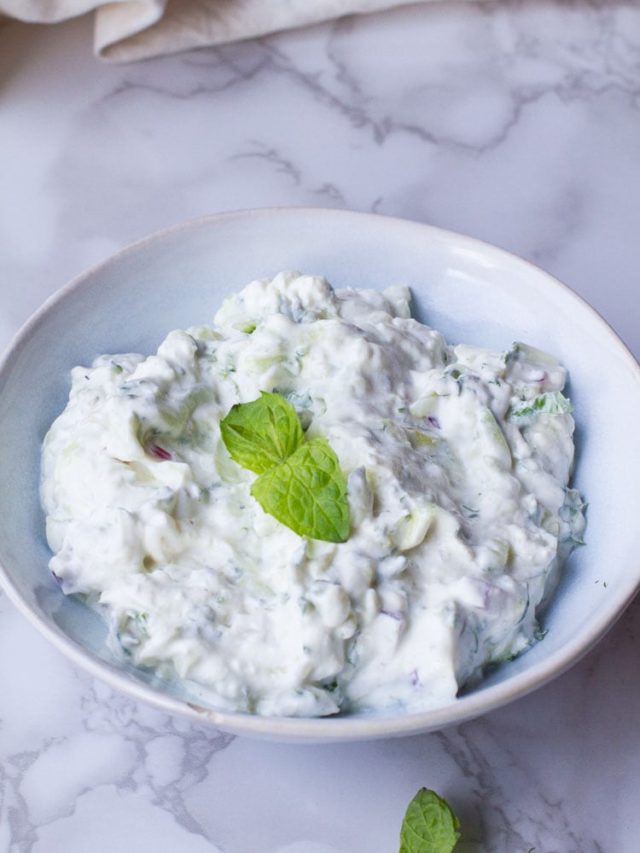 Indian raita in a blue bowl, garnished with mint leaves.