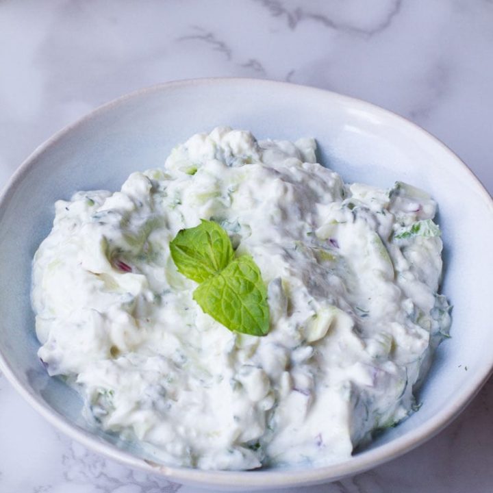 Indian raita in a blue bowl, garnished with mint leaves.