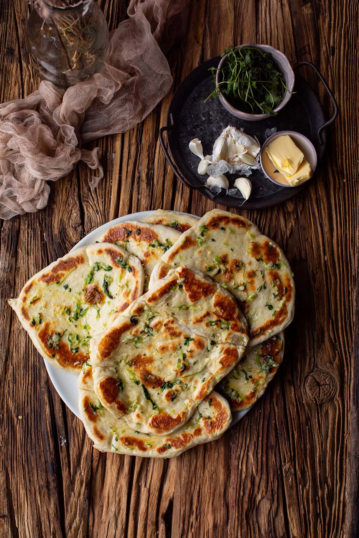 A large white plate with garlic naan. Seen from above.