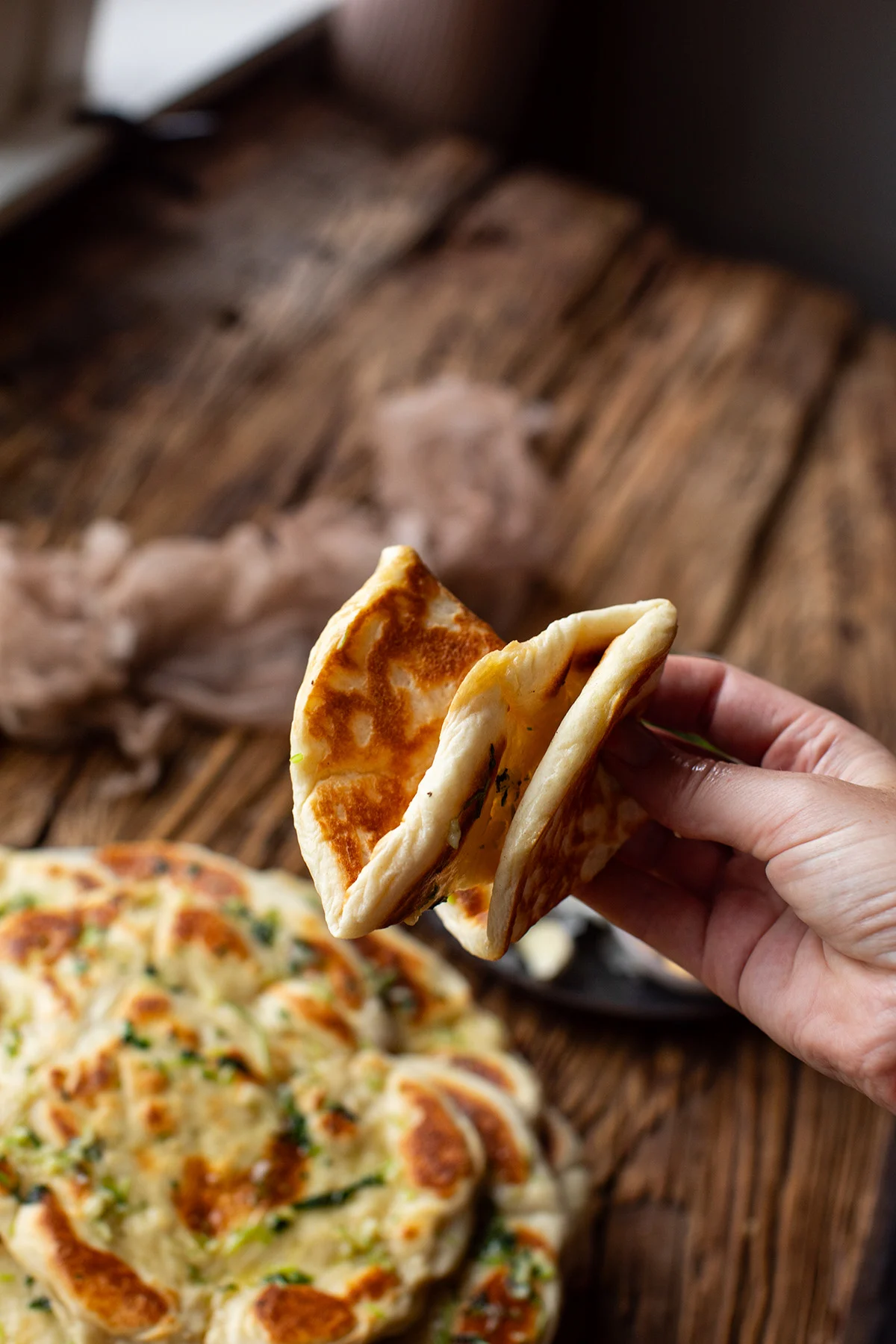 Hands showing the softness of the naan by crunching it together.