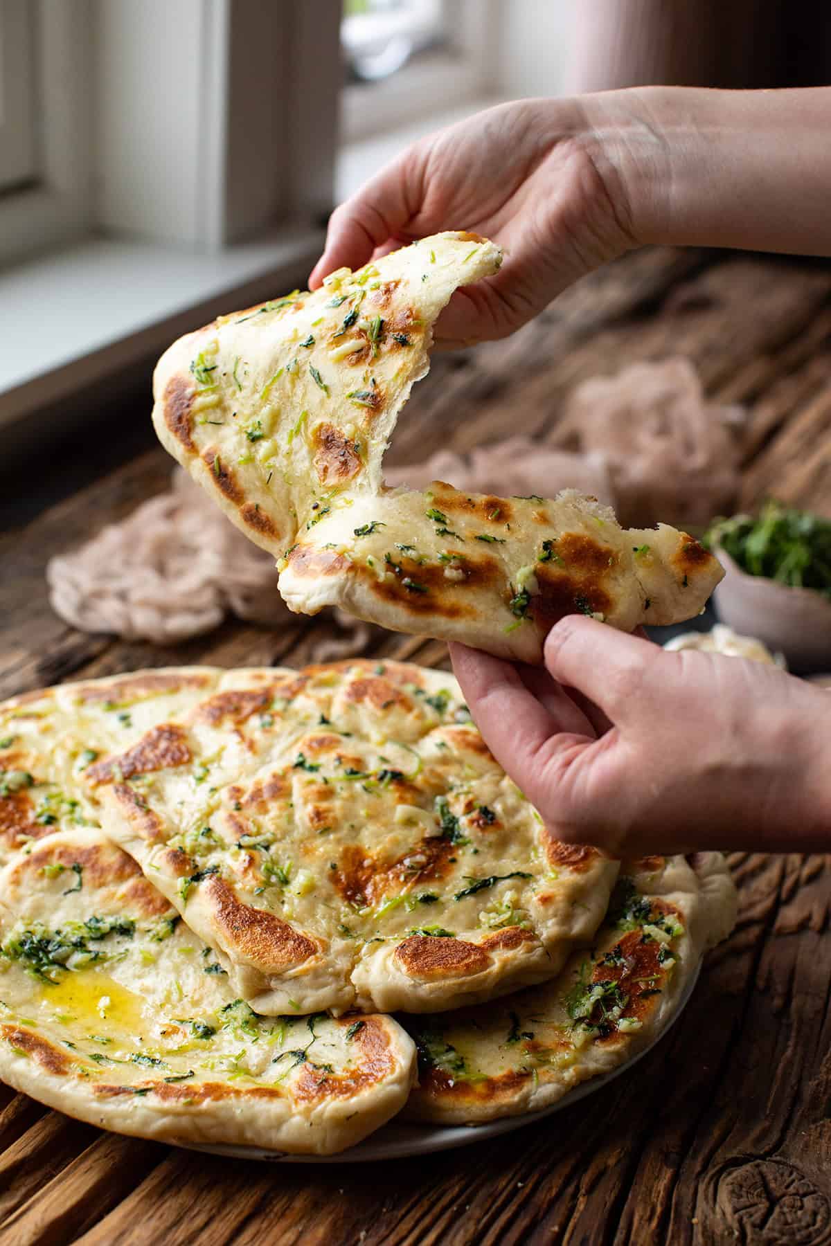 Hands tearing a piece of naan.
