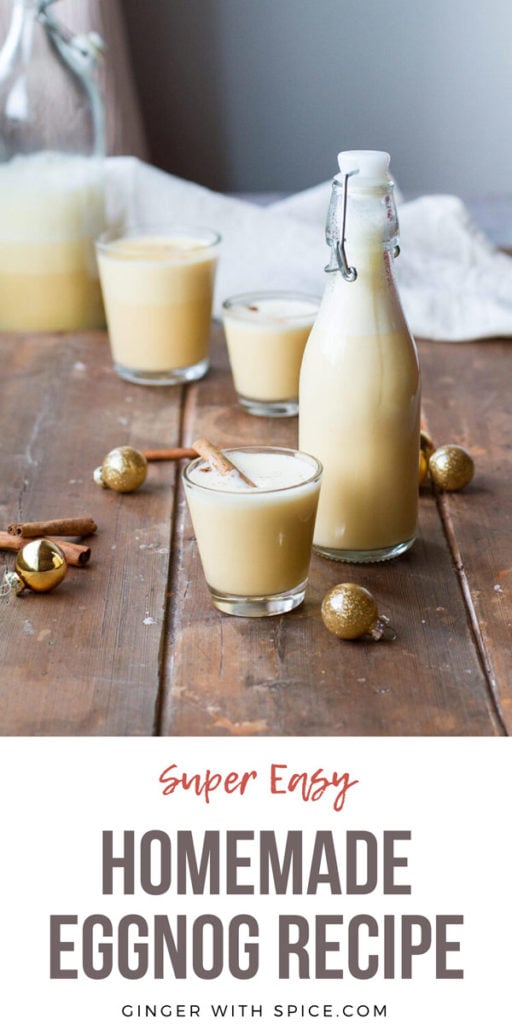 Glass and bottle with eggnog. Gold ornaments around on a wooden table. Pinterest pin.