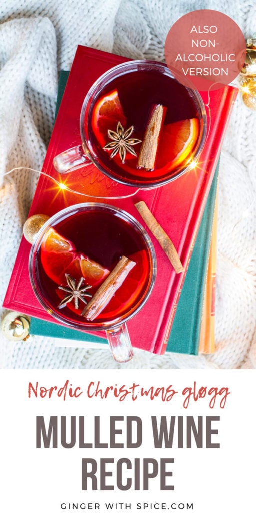 Two glasses with mulled wine, cinnamon sticks, star anise and clementine slices on a red book, white background and flatlay. Pinterest pin.
