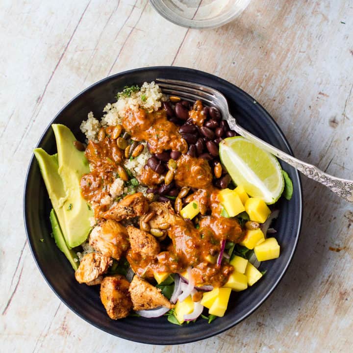 One black bowl filled with quinoa, lime chicken, mango, avocado and chipotle sauce.