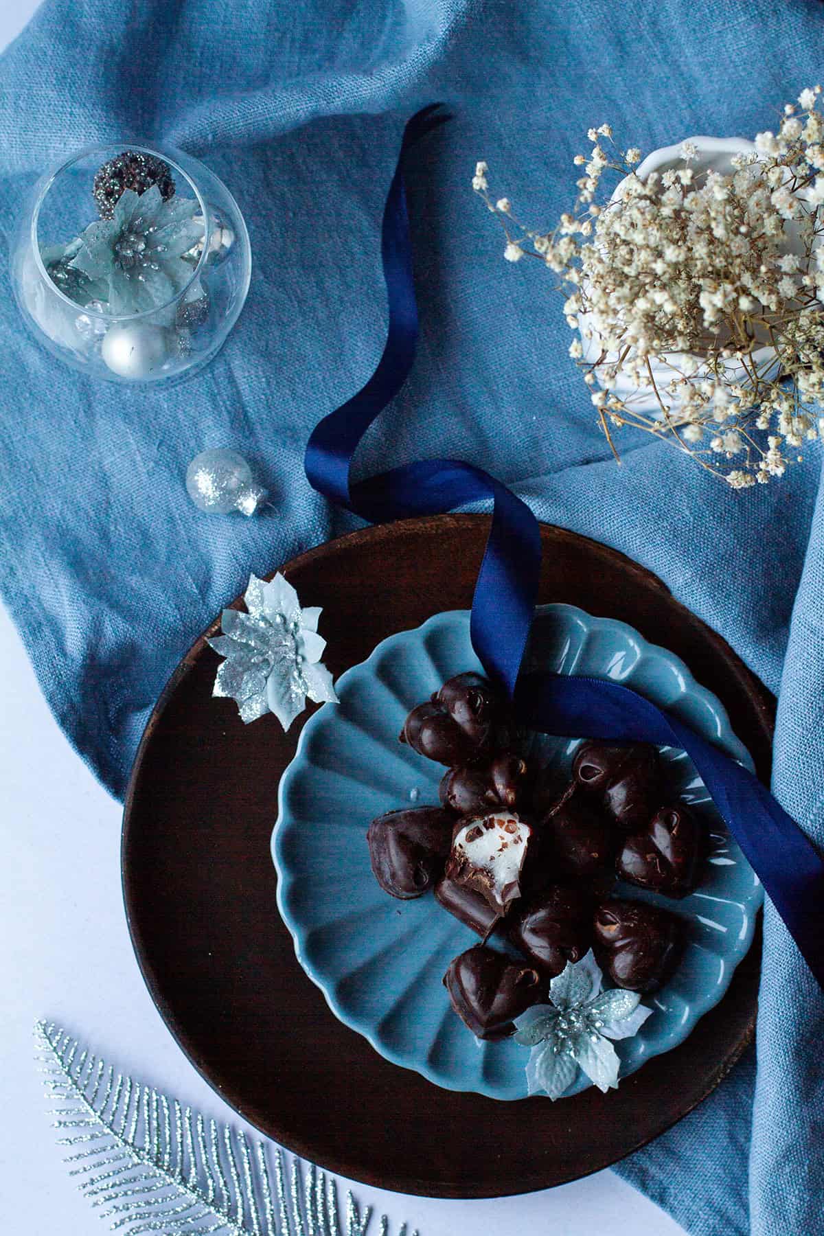 Dark chocolares on a blue plate, one cut open to show the peppermint filling.