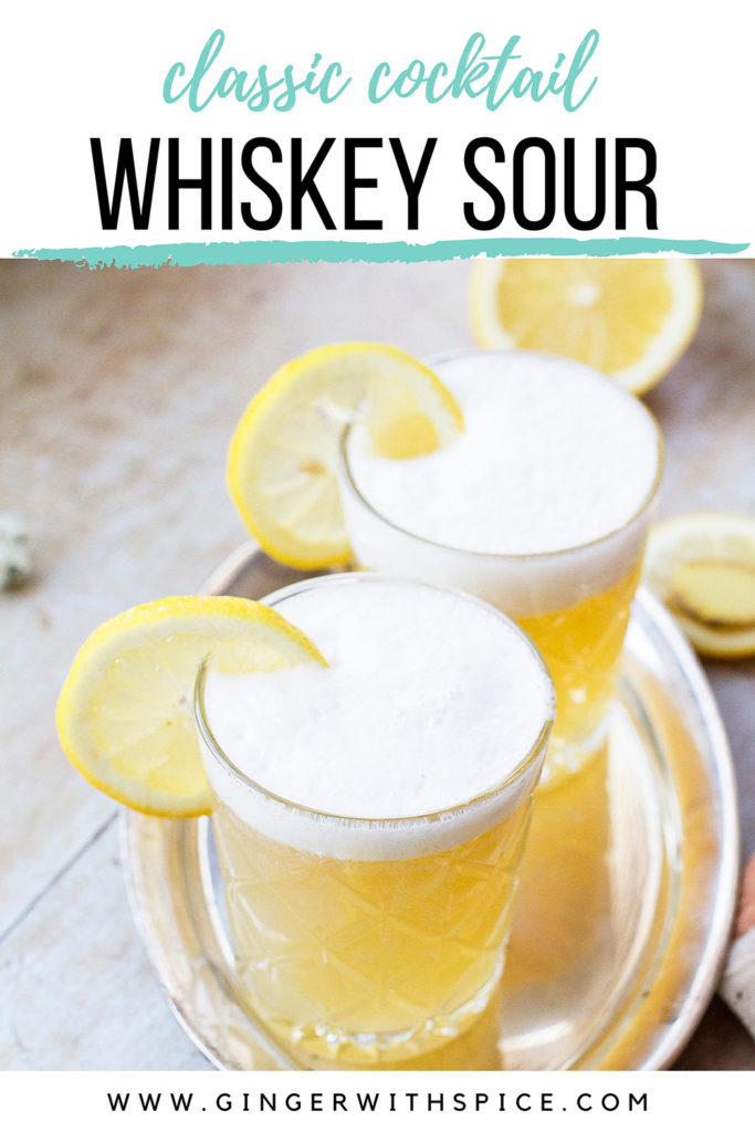 Two glasses with whiskey sour and a frothy top, garnished with lemon slices. Pinterest pin.