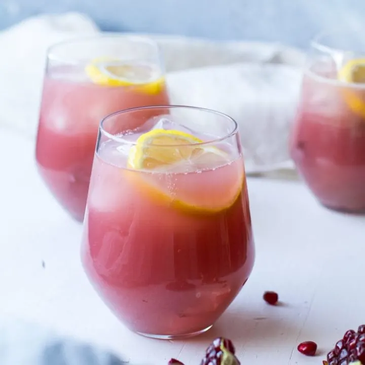 Glass with cucumber pomegranate vodka lemonade. White background.