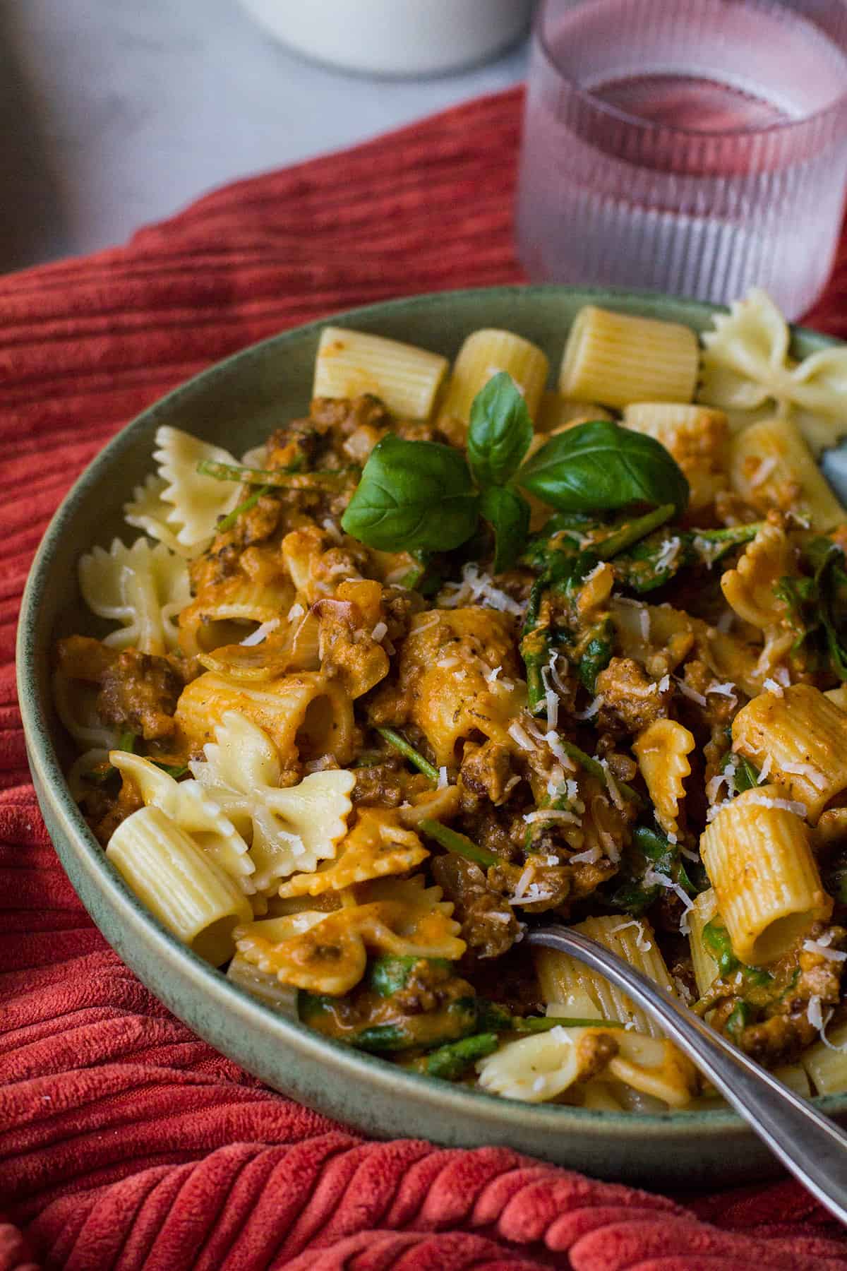 Green bowl with pasta and pumpkin sauce.