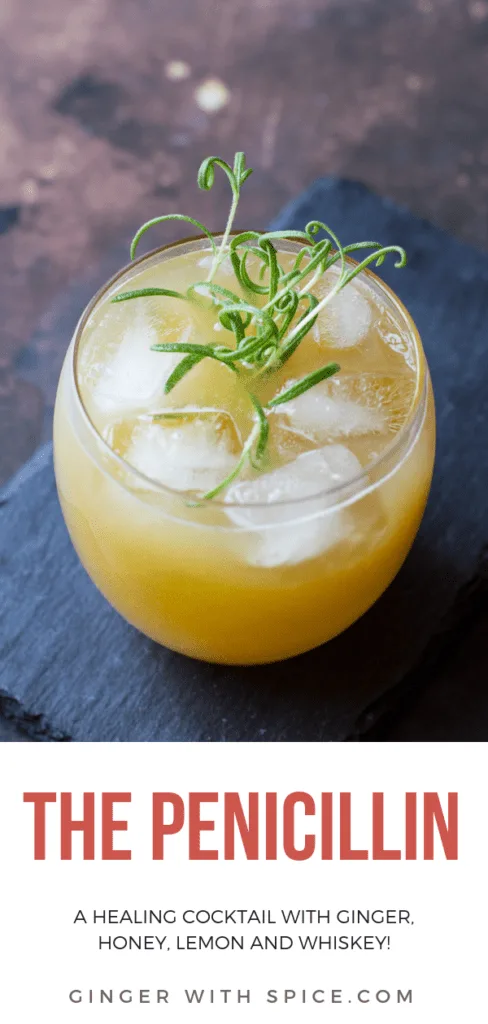 Penicillin cocktail with ice cubes and rosemary sprig in a round class. On top of a stone plate. Pinterest pin.
