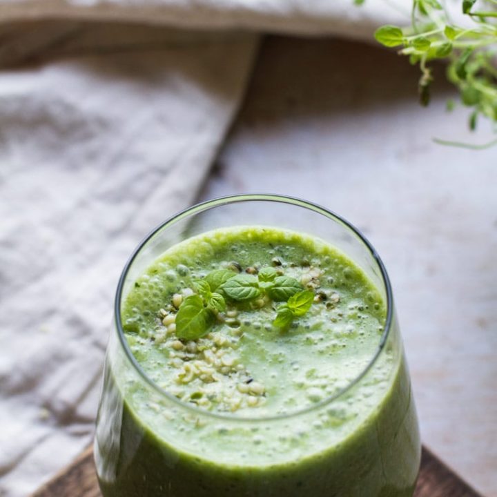 Photo of green smoothie recipe with focus on the texture of the smoothie. Beige tablecloth in the background.
