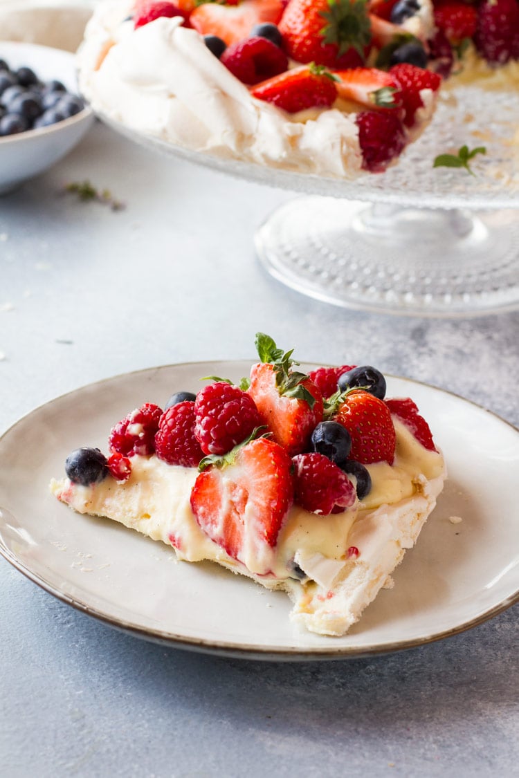 A slice of pavlova cake with fresh berries and pastry cream.