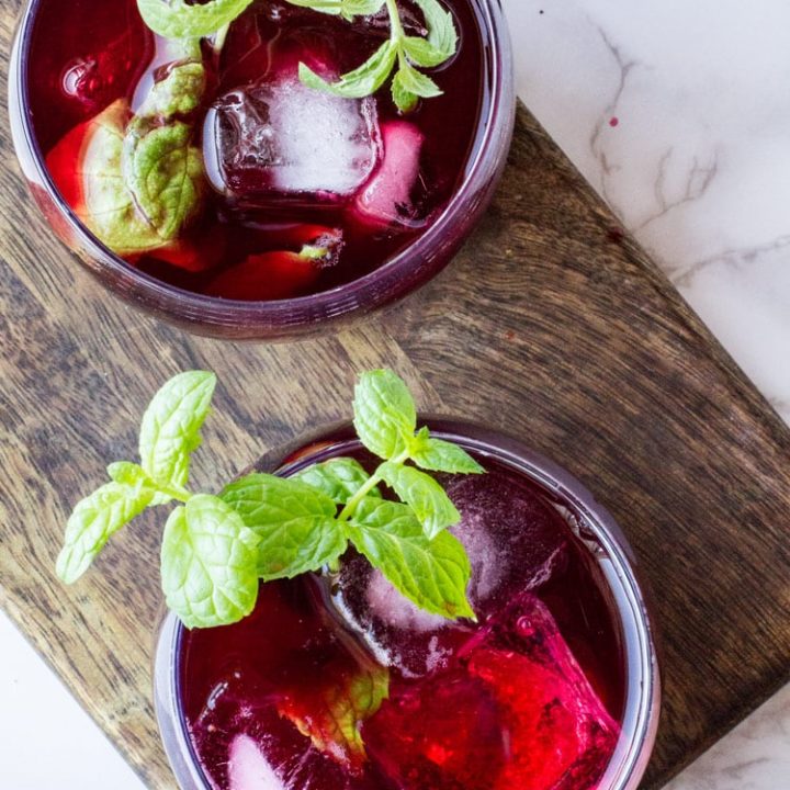 Two glasses with hibiscus tea and mint sprigs. Flatlay.