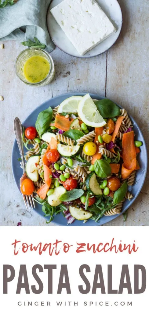 Healthy Pasta Salad with tomatoes and zucchini on a dark plate. Pinterest pin.