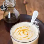 Clear glass cup with apple caramel latte macchiato and a drizzle of caramel sauce.