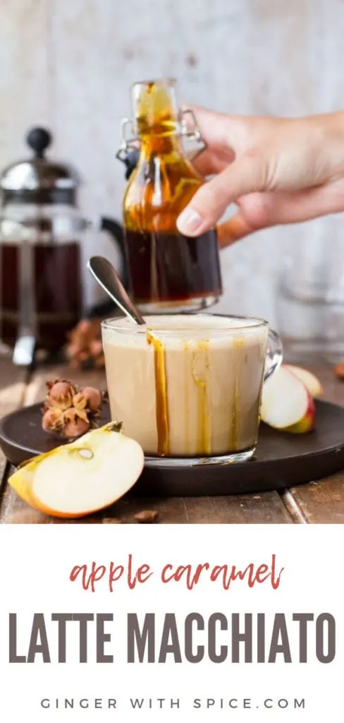 Glass cup with apple caramel latte macchiato, drizzle with caramel on the edges, hand holding glass jar with caramel in the background. Pinterest pin.