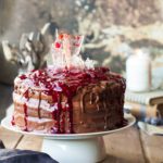 Halloween style black forest cake with sugar glass shards and cherry sauce on top.