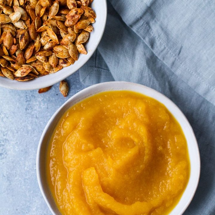 Pumpkin puree in a blue bowl on a blue table, flatlay.