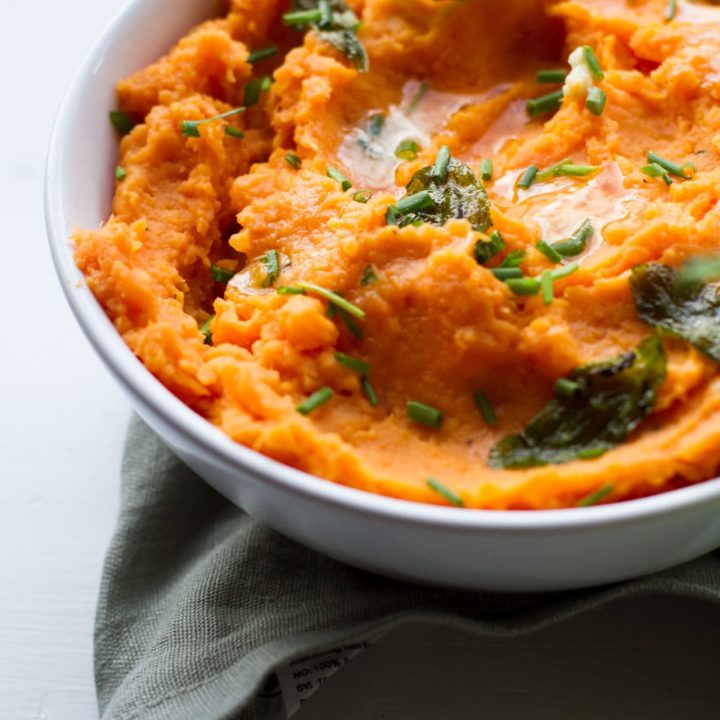 Sweet potato mash with chopped sage leaves and melted butter on top.