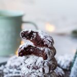 A stack of chocolate crinkle cookies, two top cookies are open in two.
