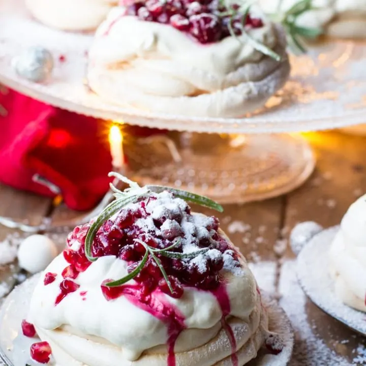 Christmas Pavlova Dessert with whipped eggnog cream and cherry sauce dripping down the sides. More in the background.