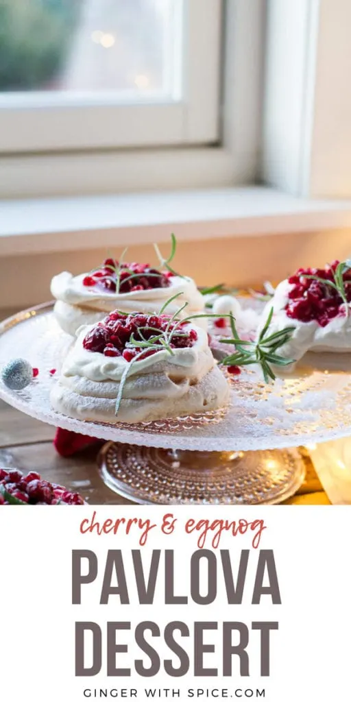Three Christmas Pavlova Desserts with eggnog cream and cherry sauce, garnished with rosemary sprigs. Pinterest pin.