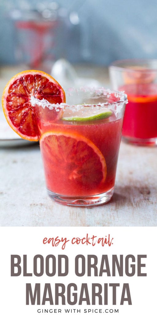 Close-up of one glass with blood orange margarita, garnished with blood orange on the side and in the drink. Pinterest pin.