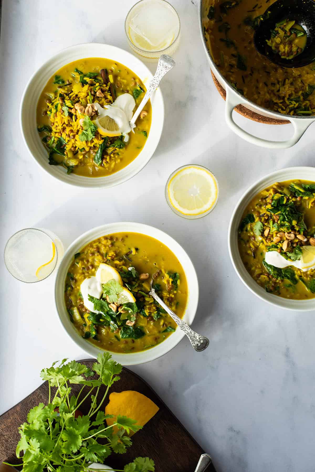Three bowls and a casserole of lentil curry seen from above.
