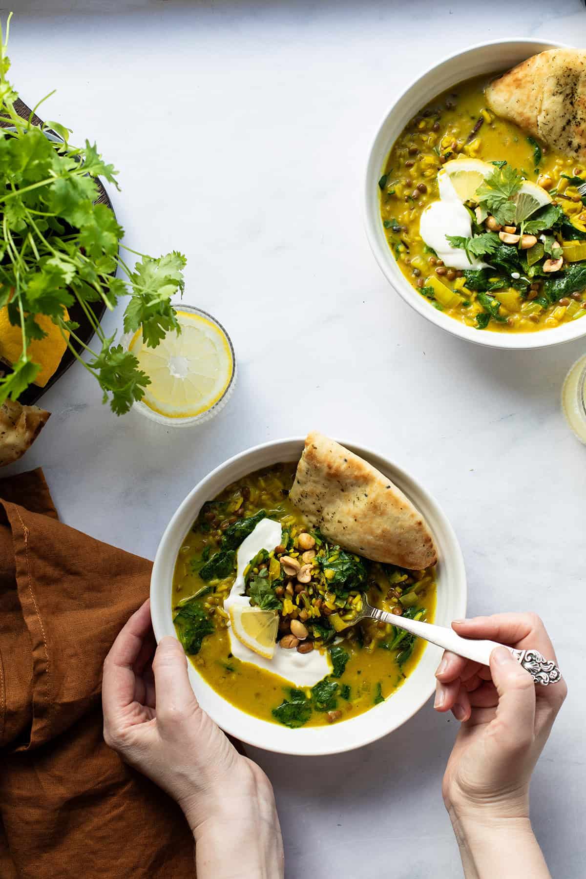 Hands holding a bowl of lentil curry.