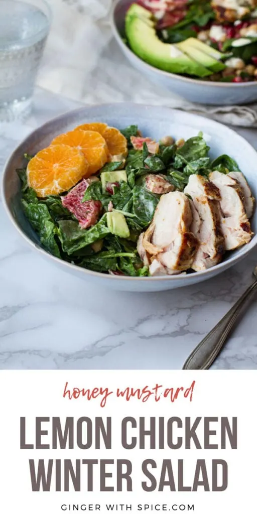 A blue bowl with spinach salad topped with sliced chicken and clementine. Pinterest pin.