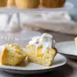 One lemon meringue cupcake cut open to show lemon curd oozing out.