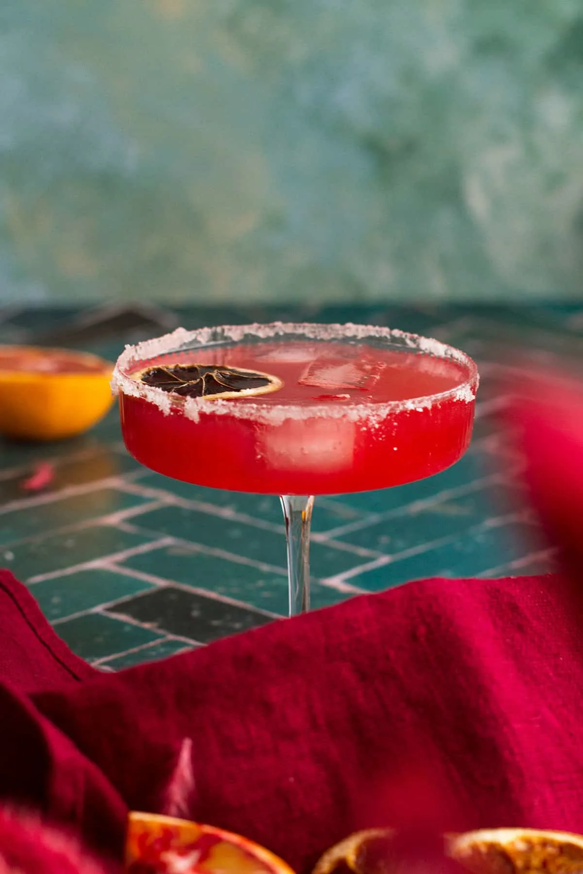 Blood orange margarita in a coupe glass and green background.