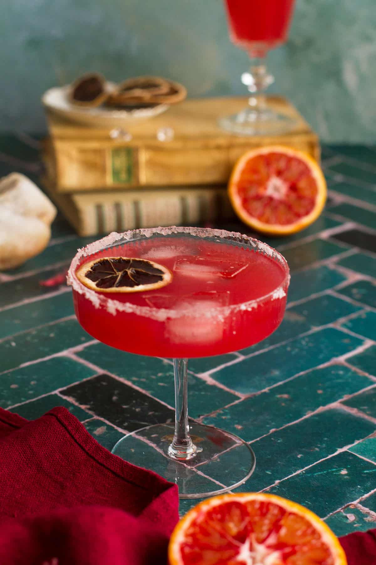 Bright red margarita in a stemmed glass, green background.