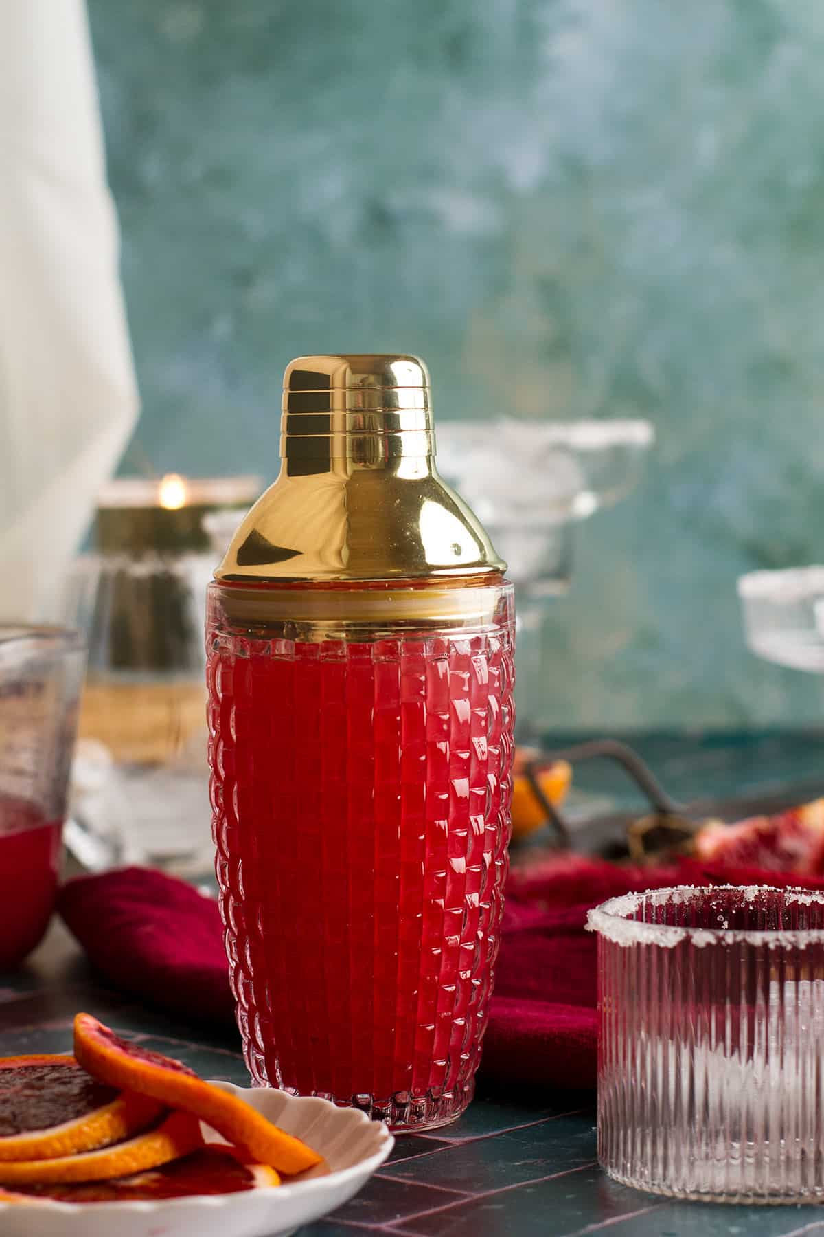 A bright red cocktail in a glass cocktail shaker.