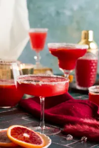 Serveral different styled glasses filled with a bright red margarita.