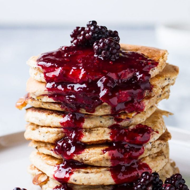 Lemon Poppyseed Pancakes with blackberry syrup down their sides.