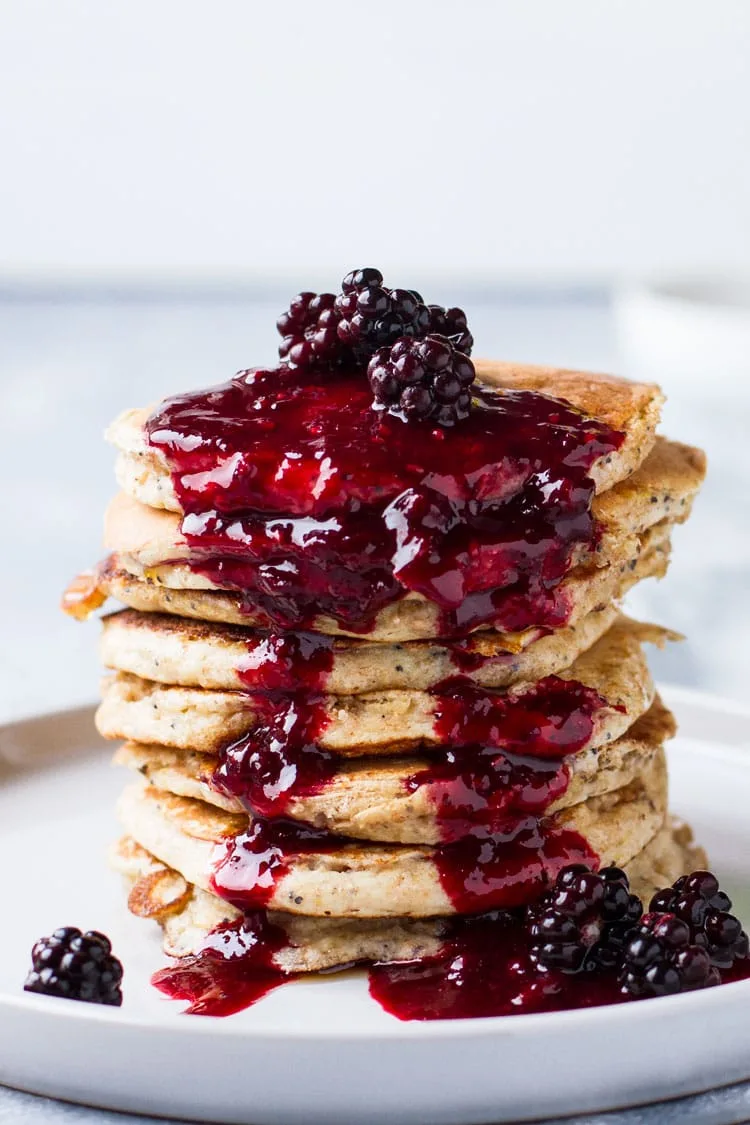 Lemon Poppyseed Pancakes with blackberry syrup down their sides.