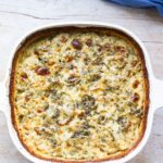 White casserole with scalloped potatoes and a cheesy top. Blue linen on the side.