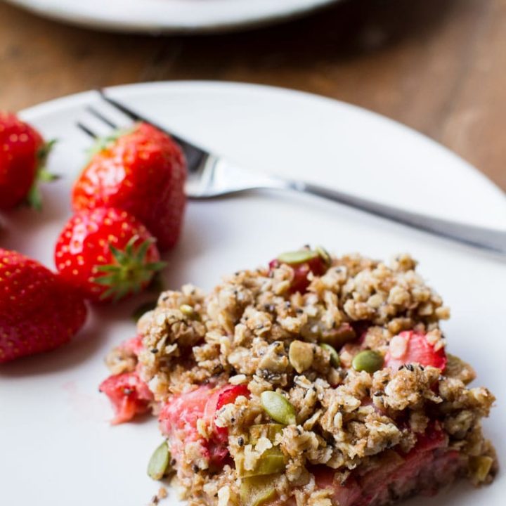 Oatmeal bar, strawberries and a fork on a white plate.