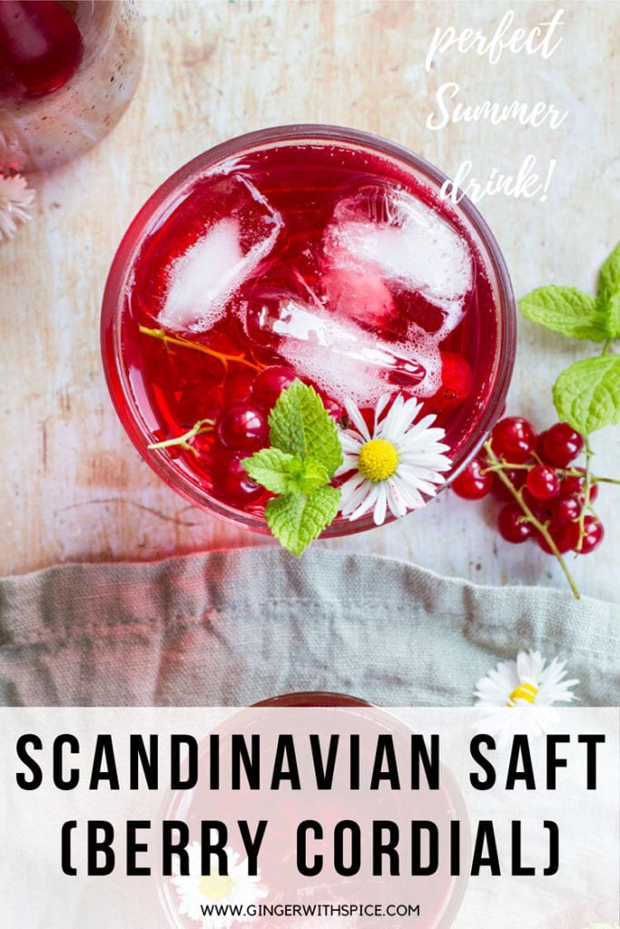 Glass with red drink and ice cubes, garnished with flower, mint leaves and red currants. Flatlay. Pinterest pin.