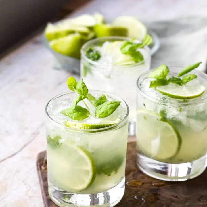 Three glasses with mojito, garnished with lime and fresh mint.