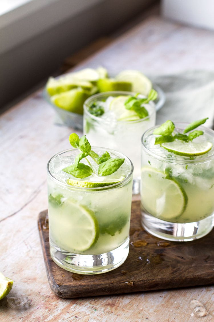 Three glasses with mojito, garnished with lime and fresh mint.