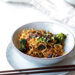 Pork and broccoli stir fry with noodles. Chopsticks on the side.