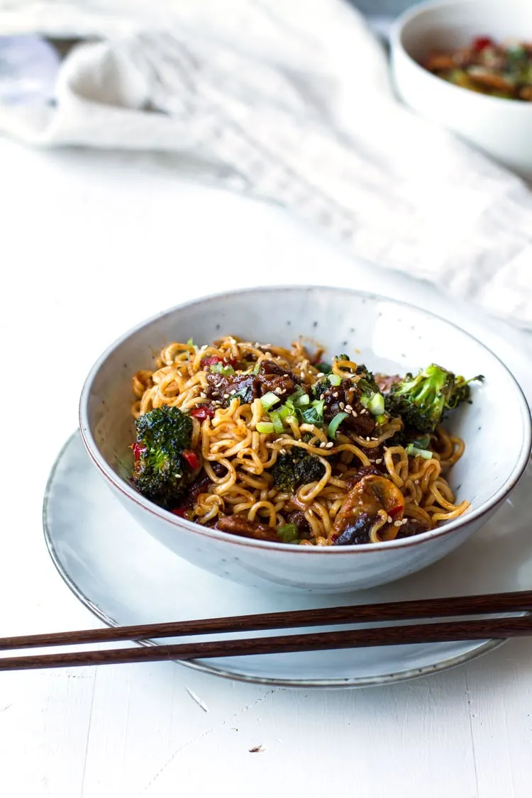 Pork and broccoli stir fry with noodles. Chopsticks on the side.