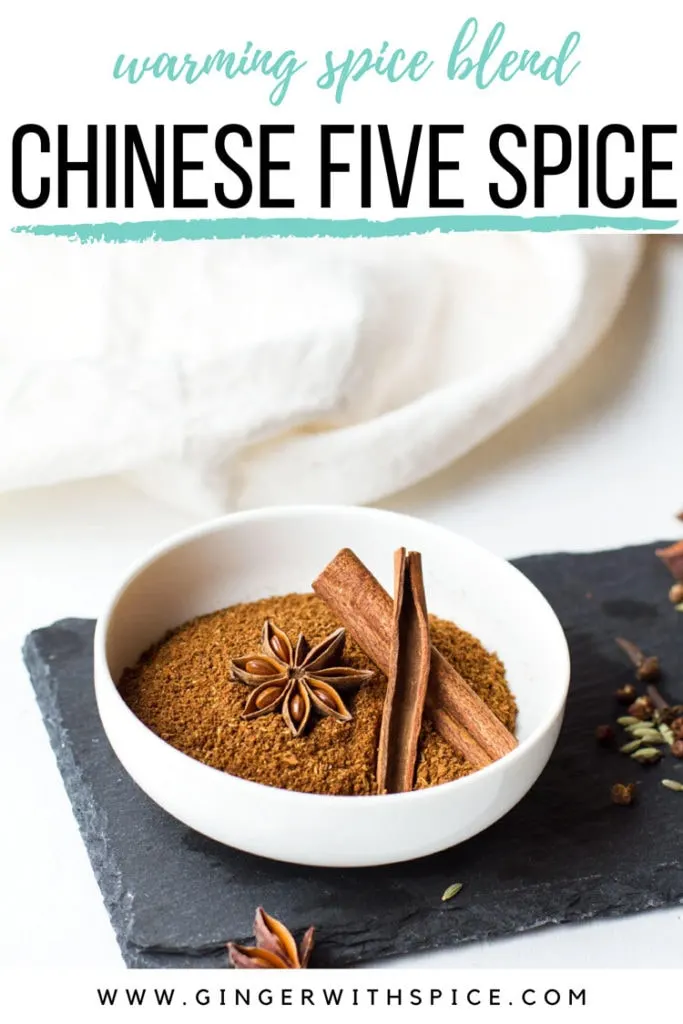 Chinese five spice in a small white bowl, garnished with star anise and cinnamon sticks. Pinterest pin.