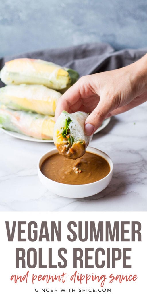 Hand holding a sliced open summer roll dipped in peanut sauce. Pinterest pin.
