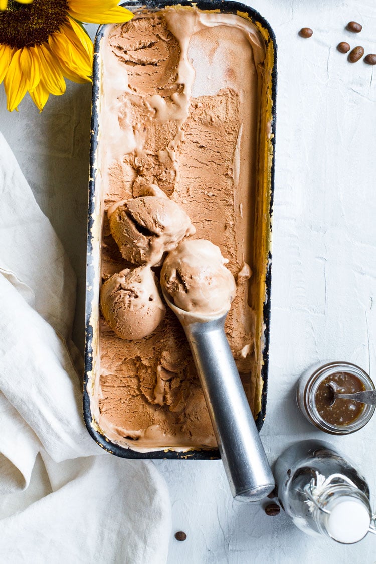 Flatlay of bread pan with chocolate ice cream and three scoops. Caramel sauce and Kahlua on the side.